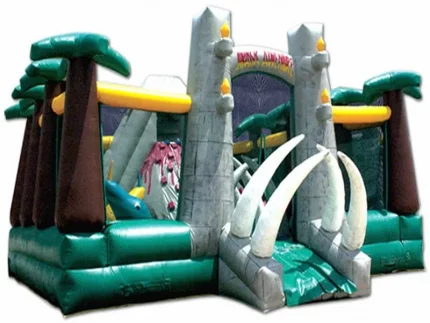 Dinosaur-themed jumping castle with tusks, trees, and climbing features. Perfect for events. Buy high-quality inflatables online in Australia today!